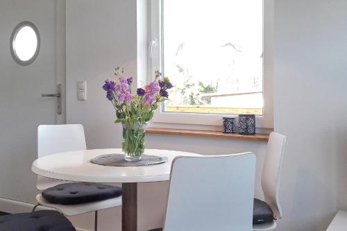 a white dining room table with a vase of purple flowers at Fewo Dobra in Lübbenau