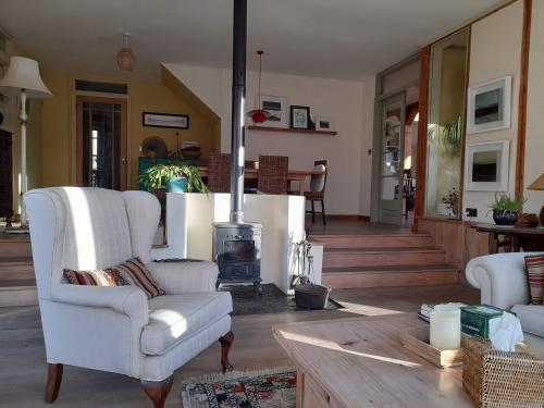 a living room with two white chairs and a fireplace at Kenmare Eco Lodge in Kenmare