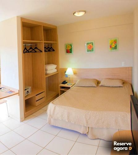 a bedroom with a bed and a desk and shelves at FLAT Golden Dolphin Express in Caldas Novas