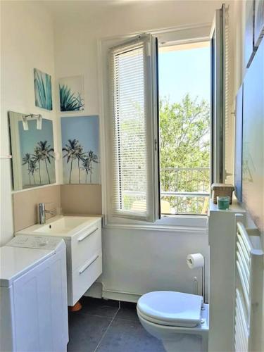 une salle de bain avec toilettes, lavabo et fenêtre dans l'établissement Appartement avec terrasse entre Versailles et Paris, à Marnes-la-Coquette