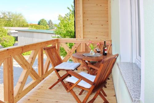 a wooden balcony with a table and a glass of wine at Fewo Dobra in Lübbenau