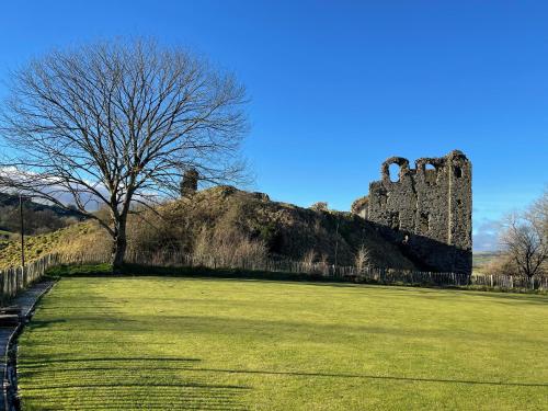 a castle sitting on top of a grass field at Beech Cottage with Clun Castle View in Clun
