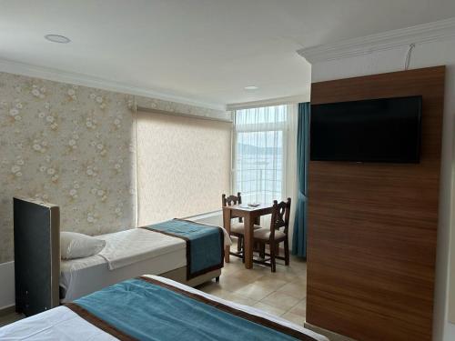 una camera d'albergo con due letti e un tavolo con una televisione di Dinc Pension a Bodrum City
