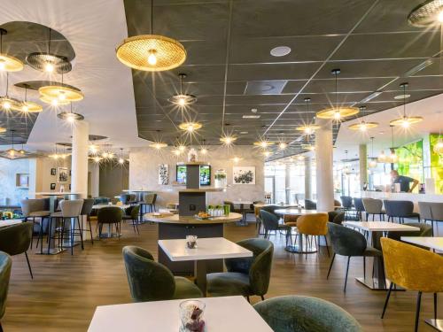 un restaurante con mesas, sillas y luces en ibis Styles Troyes Centre en Troyes