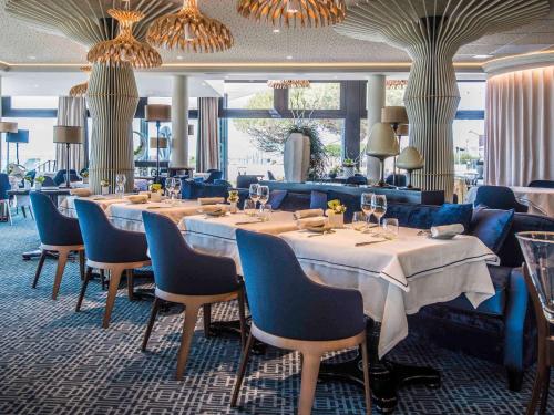 a dining room with tables and chairs and chandeliers at La Grande Terrasse Hotel&Spa La Rochelle MGallery Hotel Collection in Châtelaillon-Plage