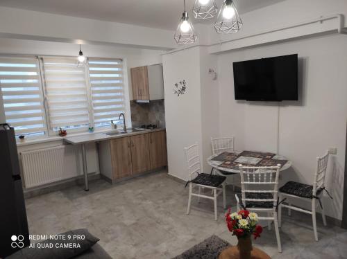 uma cozinha com uma mesa e uma televisão na parede em Nairda apartament em Suceava