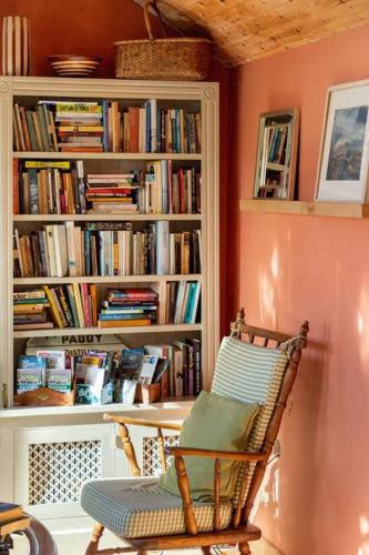 a room with a chair and a book shelf with books at Kenmare Eco Lodge in Kenmare