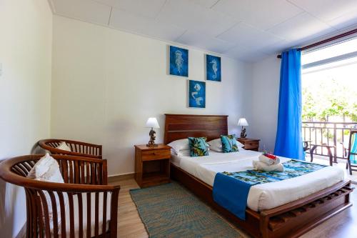 a bedroom with a bed and a balcony with blue curtains at Chez Marston in La Digue