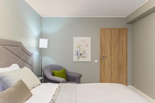 a bedroom with a bed and a chair and a door at ARA Apart Hotel #2 in Braşov