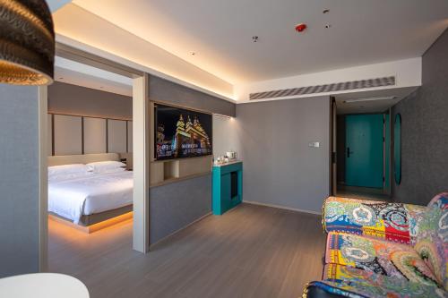 a bedroom with a bed and a couch and a tv at Rongye Hotel - Gaozhuang Xishuangjing Starlight Night Market Branch in Jinghong