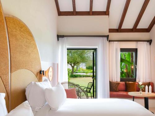 SO/ Sotogrande Spa & Golf Resort Hotel في سوتوغراندِ: غرفة نوم مع سرير وغرفة معيشة