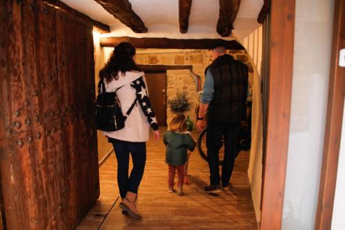 a woman and a man and a child walking down a hallway at La Casa del Castell in Horta de San Joan