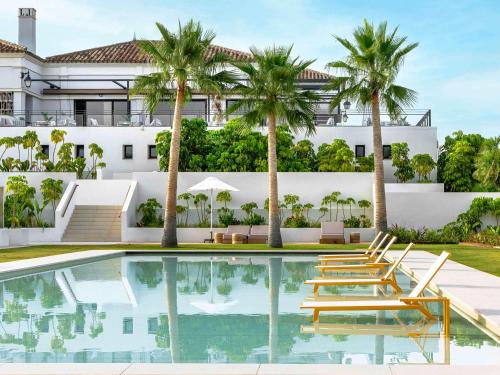 una imagen de una piscina con sillas y palmeras en SO/ Sotogrande Spa & Golf Resort Hotel, en Sotogrande