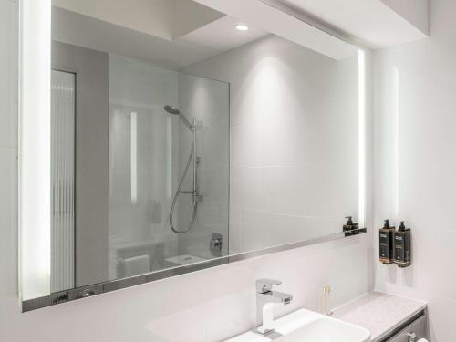 a bathroom with a large mirror and a sink at Novotel Sydney City Centre in Sydney