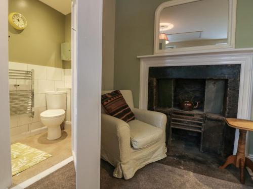 a living room with a chair and a fireplace at Printers Cottage in Cockermouth