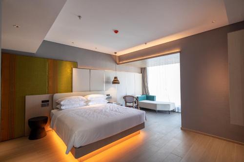 a bedroom with a bed and a desk and a chair at Rongye Hotel - Gaozhuang Xishuangjing Starlight Night Market Branch in Jinghong