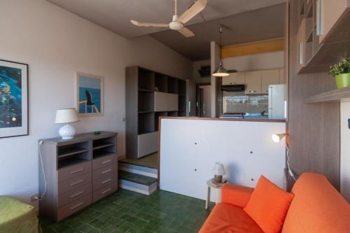 a living room with an orange couch and a kitchen at Monolocale CM in Follonica