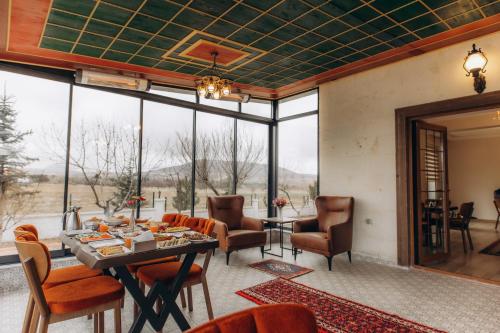 a living room with a table and chairs and windows at Cappadocia Villa Comfort in Nevşehir