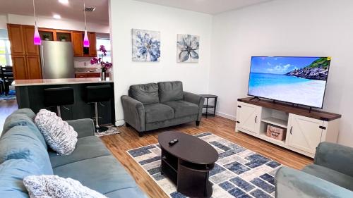 a living room with a couch and a flat screen tv at LuxCoral - 4 Min walk to beach! in Cape Canaveral