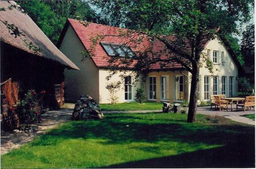 a white house with a red roof and a yard at Fewo Fischotter in Lehde