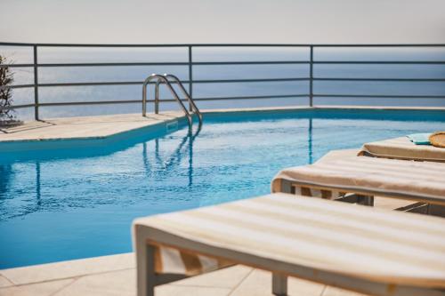 uma piscina com duas espreguiçadeiras ao lado em Athens Riviera Villa em Anavissos