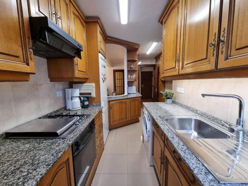 eine große Küche mit Holzschränken und einem Waschbecken in der Unterkunft VibesCoruña- Ponte 2 in A Coruña