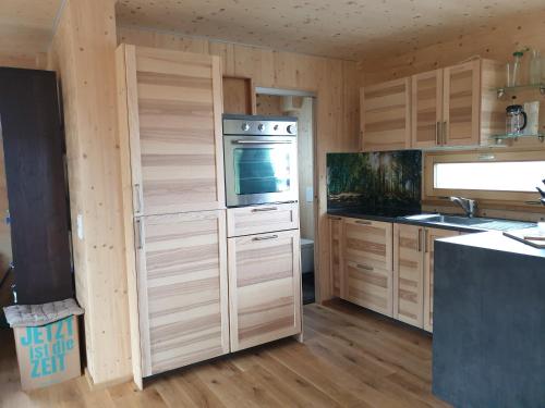 a kitchen with wooden cabinets and a stove top oven at Holzhaus am Bergheider See 