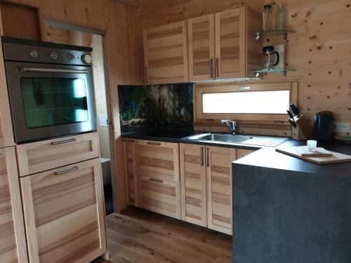 a kitchen with wooden cabinets and a sink and a stove at Holzhaus am Bergheider See 