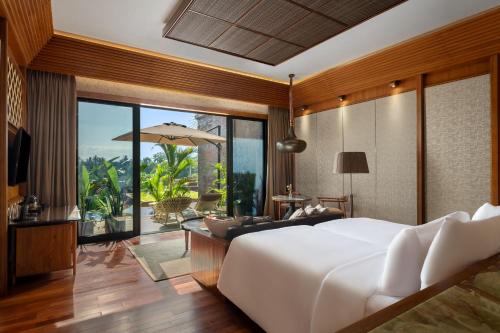 Garrya Bianti Yogyakarta في يوغياكارتا: غرفة نوم بسرير ابيض كبير وفناء