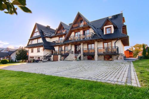 a large house with a stone driveway in front of it at Willa Królewska - Wellness SPA - widokowe Pokoje i Apartamenty in Kościelisko