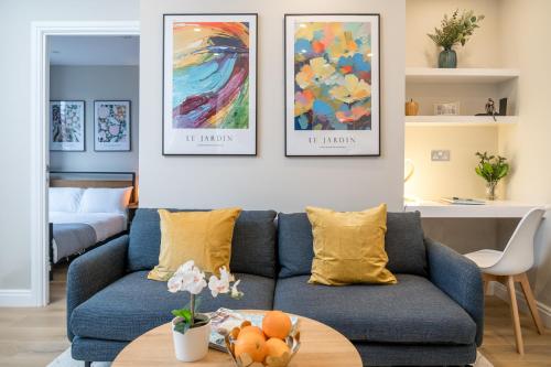 a living room with a blue couch and paintings on the wall at Tabard House Apartment London Bridge In City Of London in London