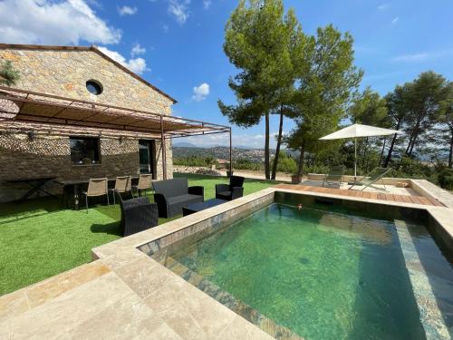 a pool in a yard with chairs and an umbrella at Charmante maison de vacances Sud France in Fayence