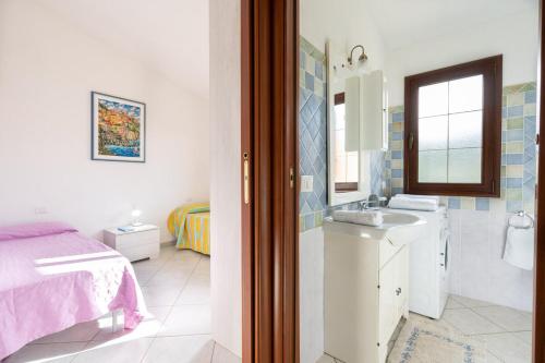 a white bathroom with a sink and a bed at Angel Village in San Teodoro