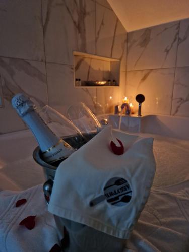 a bed with a bottle of wine and a glass at Apartmani Leburic in Prnjavor