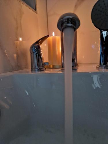 a bathroom sink with a candle and a faucet at Apartmani Leburic in Prnjavor