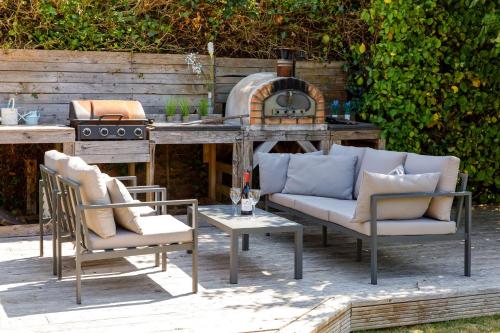 a patio with a couch and chairs and a stove at Family Seaside Retreat - 5 minutes to Beach in West Wittering