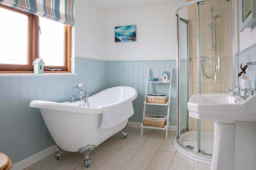 a bathroom with a tub and a sink and a shower at Tranquil Family Retreat 5 min to Beach Garden in West Wittering