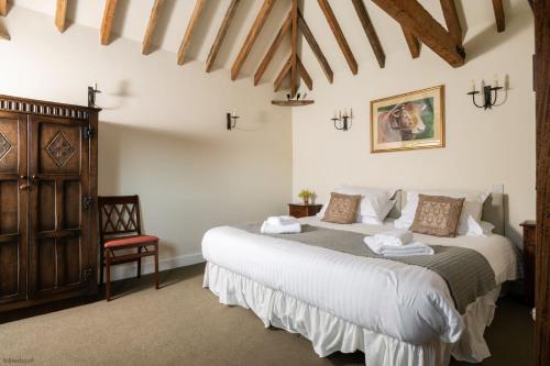 a bedroom with a large bed and a chair at Bull Pen and Cart Lodge in Herstmonceux