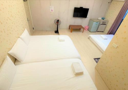 a room with two beds and a flat screen tv at 逢甲馨宿 in Hsia-shih-pi