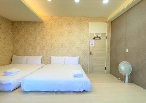 um quarto com 2 camas, uma ventoinha e uma porta em 逢甲馨宿 em Hsia-shih-pi