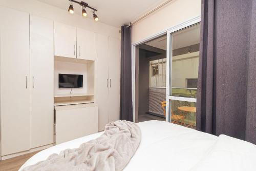 a bedroom with a bed and a kitchen with a window at Vossa Bossa VN Turiassu in Sao Paulo