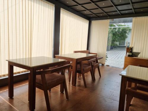 two tables and chairs in a room with windows at Peakaavu Cottages in Idukki