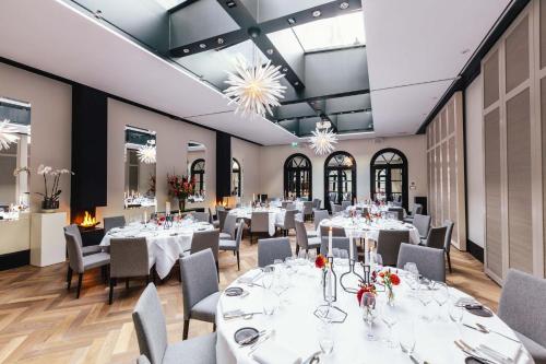 a dining room with white tables and chairs and chandeliers at The Dylan Amsterdam - The Leading Hotels of the World in Amsterdam