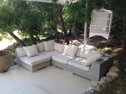 un divano bianco seduto su un patio sotto un albero di Villa a Rosa Marina con piscina a 300 m. dal mare a Rosa Marina