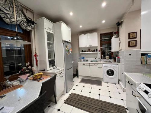 a kitchen with white cabinets and a washing machine at LiveStay Room with Free Parking in Wembley in London