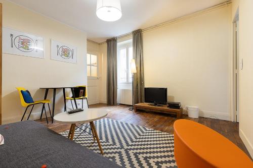 a living room with a couch and a tv at Smart Inn Fontainebleau Centre- Appartement 1 chambre in Fontainebleau