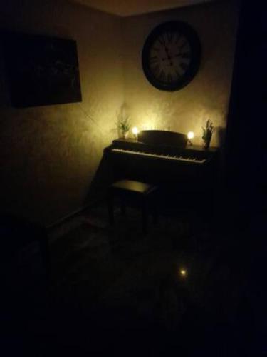 a dark room with a piano and a clock on the wall at Welcome to Rabat Technopolis, Sala jadida, the book is open, We propose a private suite in a shared apartment, Dears A rab couples you may need a marriage certificate to rent the room According to Moroccan law, Thank you in advance in Oulad Yakoub
