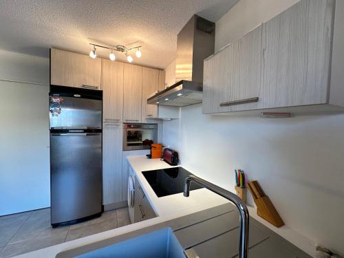 une cuisine avec un réfrigérateur et des armoires en acier inoxydable dans l'établissement Appartement studio vue sur la Marina, à Canet