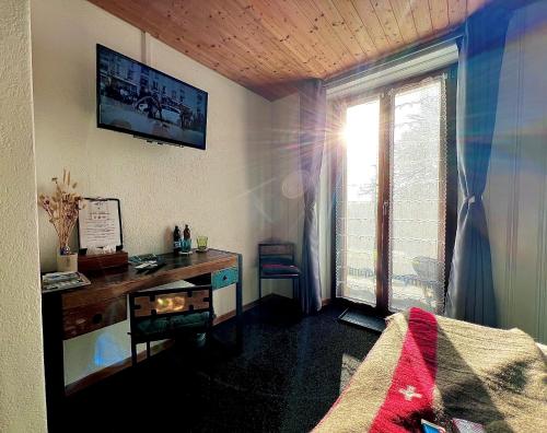 a bedroom with a desk and a window at Hôtel Restaurant Les Cernets Swiss-Lodge SSH in Les Verrières