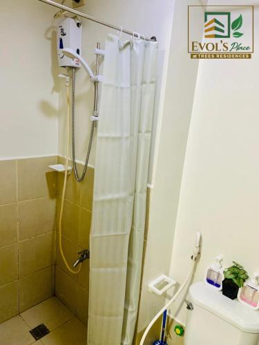 La salle de bains est pourvue d'un rideau de douche et de toilettes. dans l'établissement Trees Residences Staycation 1br/2br, à Manille